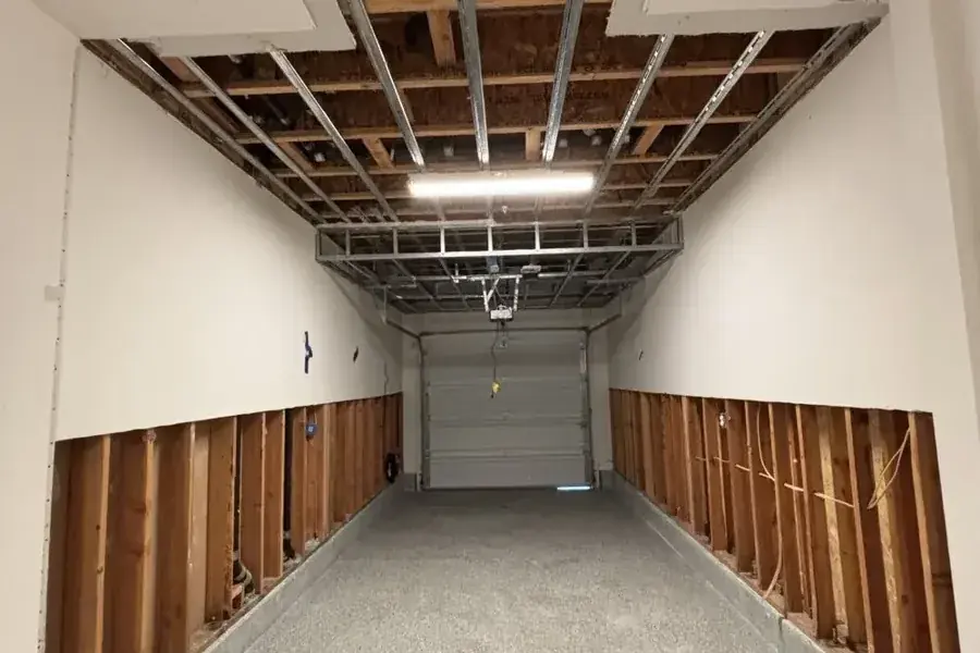 Garage drywall cut along both walls after a water heater leak