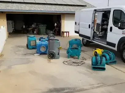 Air movers and dehumidifiers staged on a driveway before a dry-out
