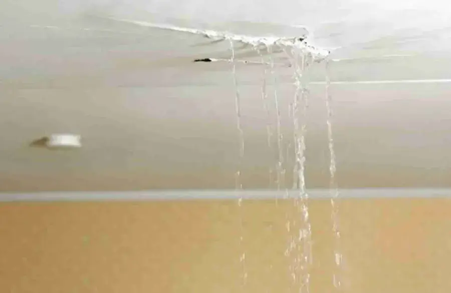 Water pouring through a cracked ceiling inside a home