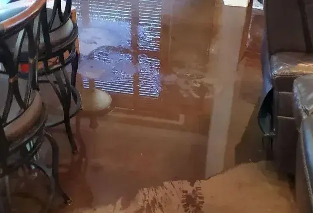 Standing water across a lower-level rec room after a sump pump failed